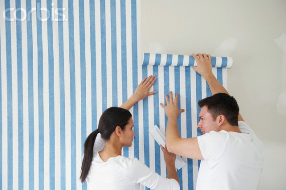 Couple applying wallpaper to wall